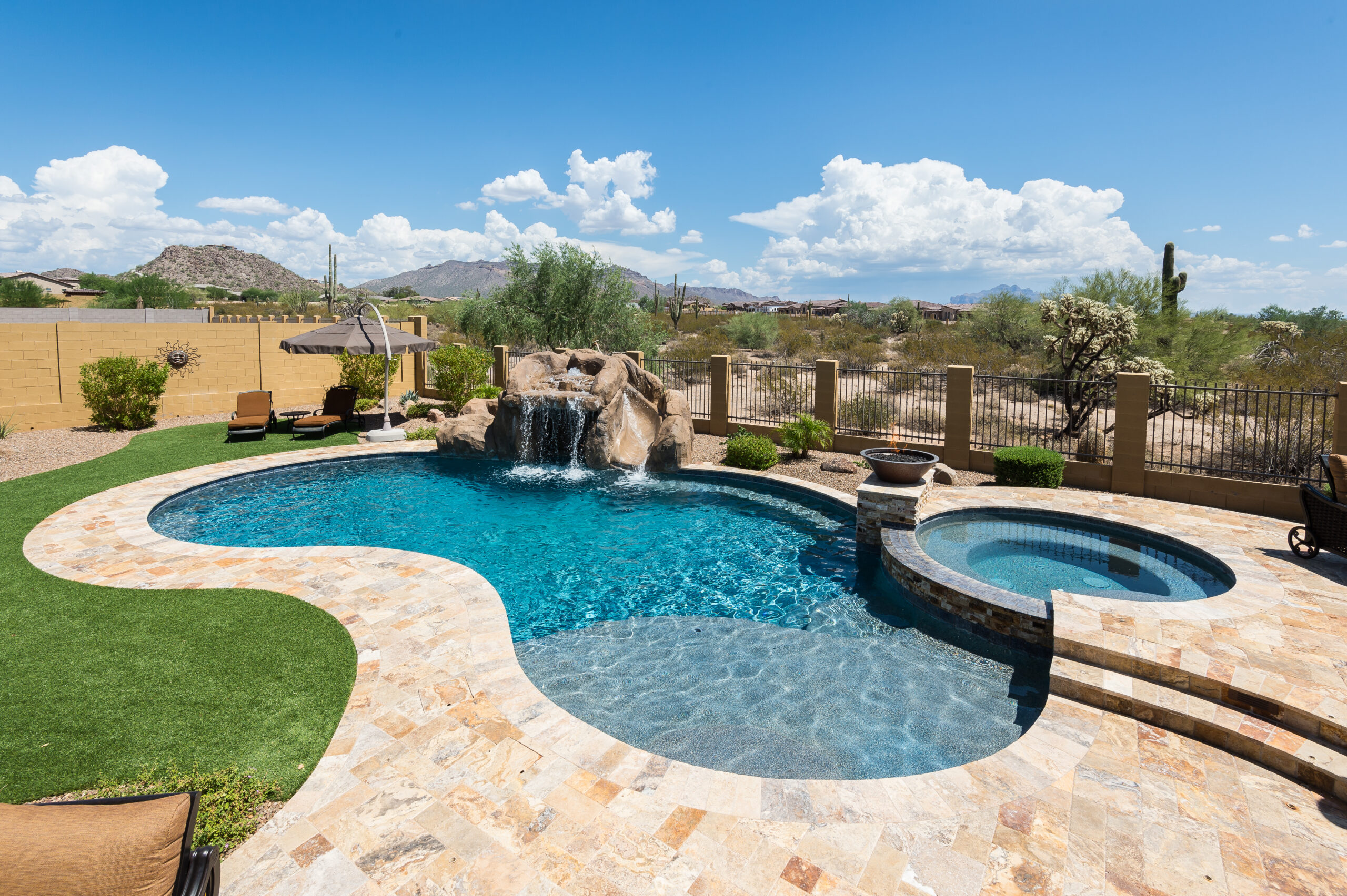 a pool with a waterfall in the middle of a backyard