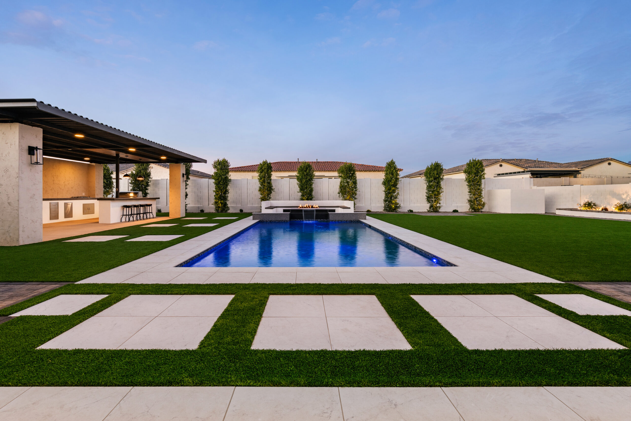 a pool with grass and a fire pit