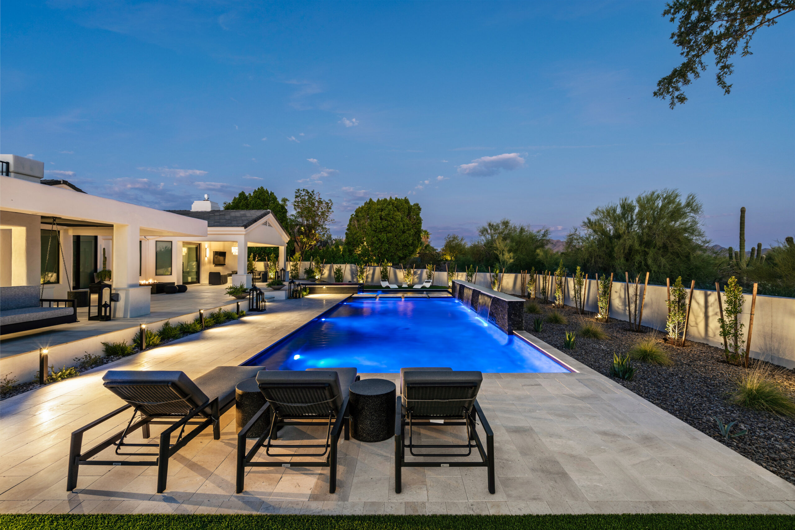 a pool with chairs and a house in the background