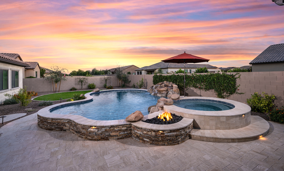 a pool with a fire pit and a stone wall